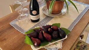 A wooden table with a bottle of wine, a potted plant, and a plate of figs. - Entire lodging in peasant house at the foot of Majella - Agricasa Caprafico (Abruzzo)