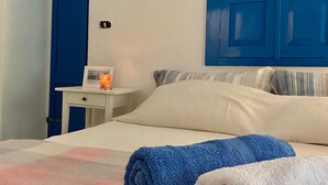 A bedroom with a bed, a nightstand, a blue door, and a white wall. - Entire lodging in peasant house at the foot of Majella - Agricasa Caprafico (Abruzzo)