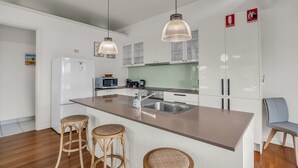 A modern kitchen with a central island, white cabinets, and two hanging pendant lights.
