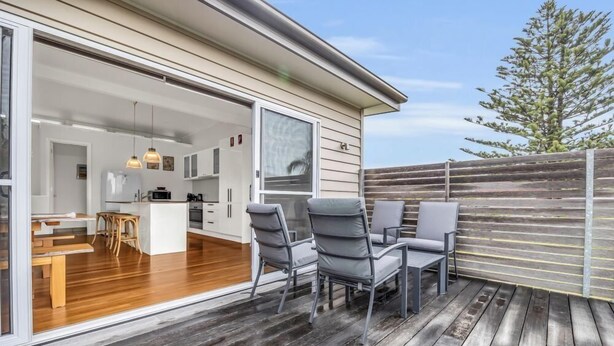 An open-plan kitchen and dining area with a wooden deck and outdoor seating.
