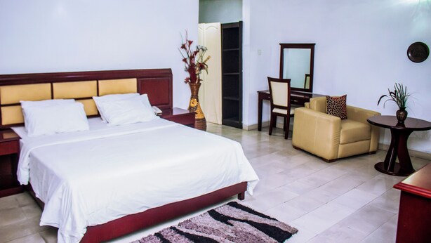 Ein Hotelzimmer mit einem großen Bett, einem Schreibtisch, einem Stuhl und einem kleinen Tisch.