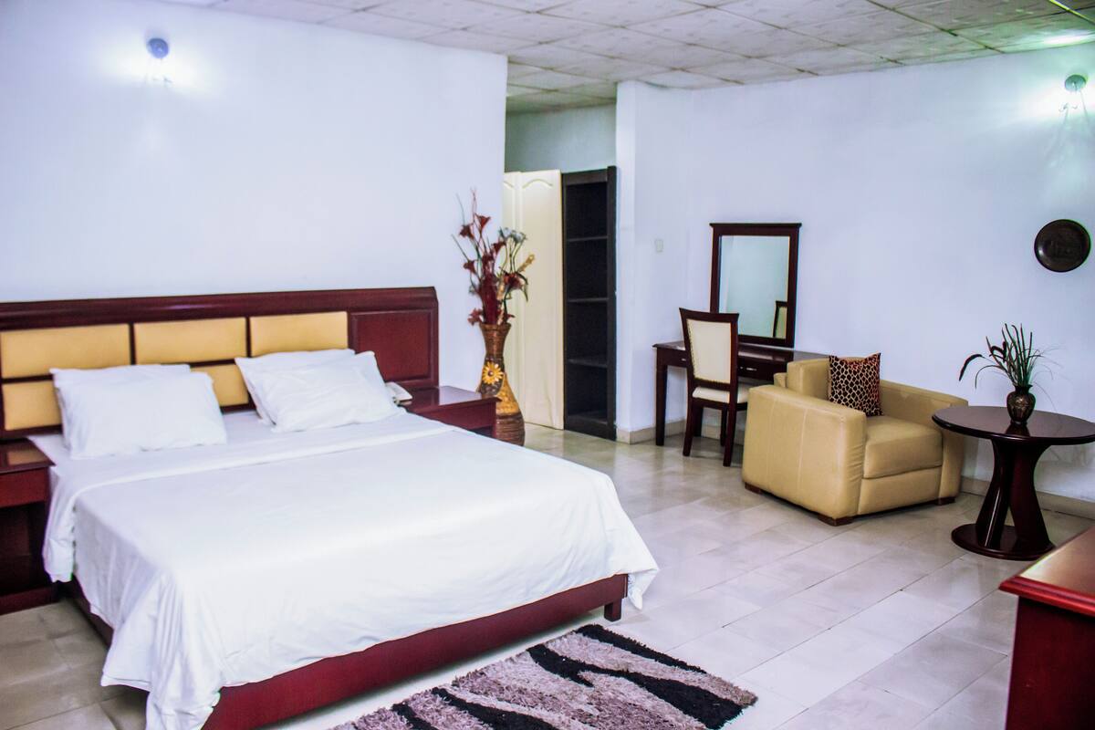 Ein Hotelzimmer mit einem großen Bett, einem Schreibtisch, einem Stuhl und einem kleinen Tisch.