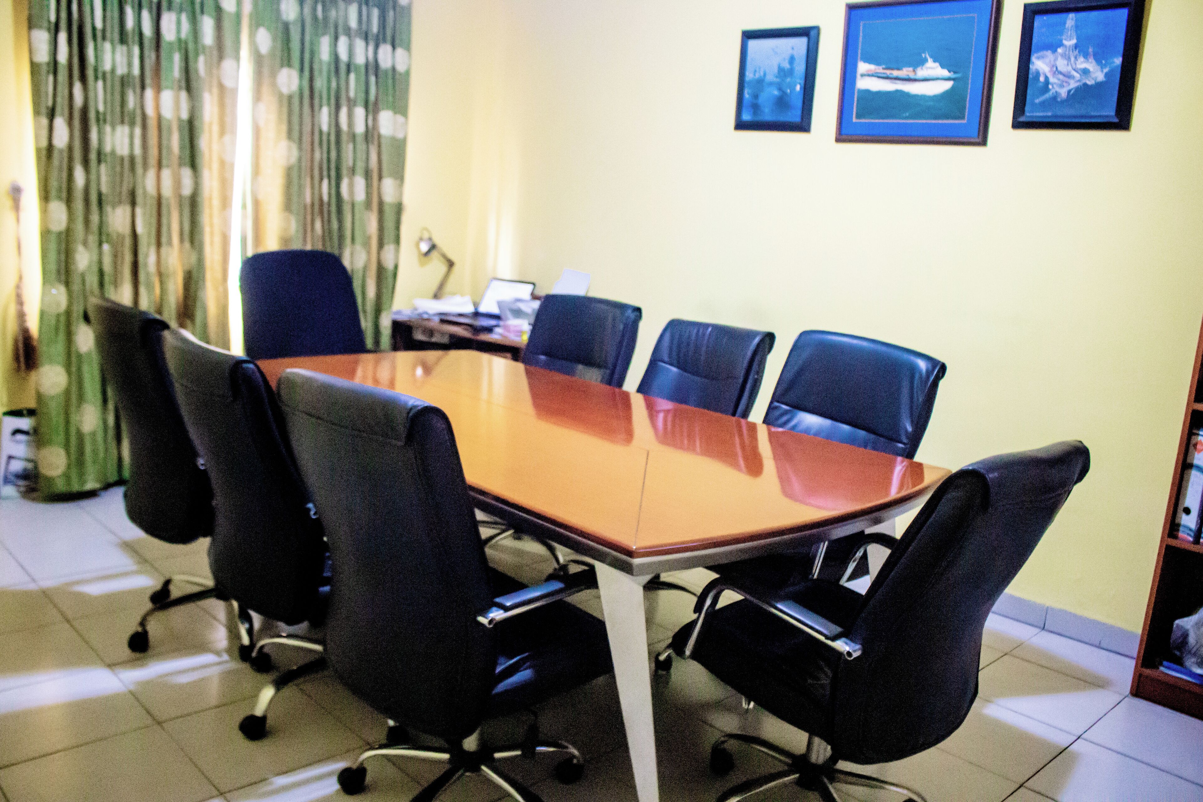 A conference room with a rectangular table surrounded by six black office chairs.