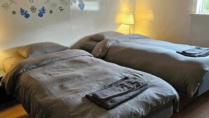 A room with two beds, a wall with floral and bird decals, a lamp, and a window.