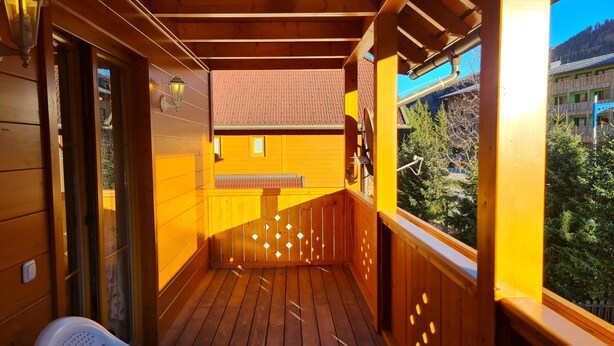 Terraza de madera con vista a un edificio y árboles.