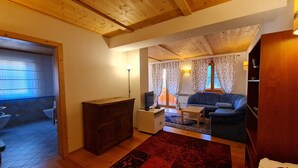 Una sala de estar acogedora con techo de madera, un sofá, una mesa de centro y un tapete estampado.