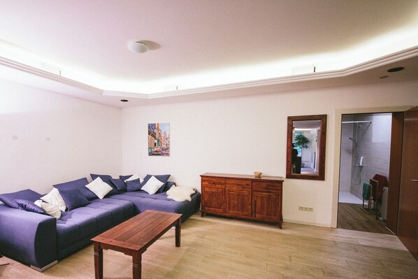 A living room with a sectional sofa, wooden cabinet, and a small table.