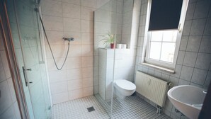 A bathroom with a glass shower enclosure, a toilet, a sink, and a window. - Room with queen size bed and bathroom, tv, Netflix, wifi (Rudolstadt)