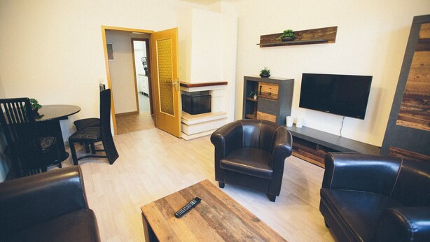 Ein Wohnzimmer mit Kamin, Fernseher und Ledersofas.