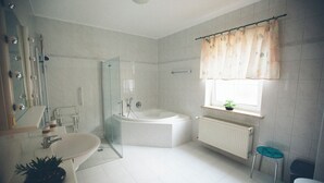 Ein Badezimmer mit einer Badewanne, einem Waschbecken, einem Spiegel und einem Fenster mit Vorhängen.