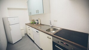 Eine kompakte Küche mit Kühlschrank, Geschirrspüler, Herd und Spüle.