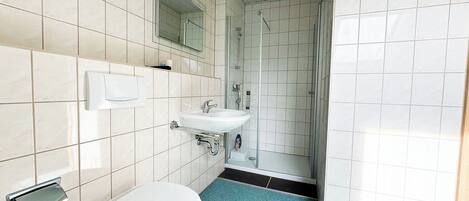 A bathroom with a toilet, sink, and shower.