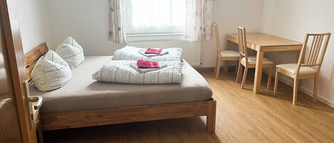 Un dormitorio con una cama, un escritorio de madera y una silla.