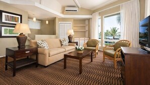 Ein Hotelzimmer mit Sofa, Sesseln, Couchtisch, Fernseher und einem großen Fenster mit Blick.