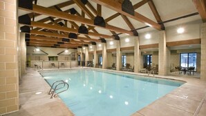 An indoor swimming pool with a tiled floor, wooden beams, and seating areas. - WorldMark Yellowstone - 1 Bedroom (West Yellowstone)