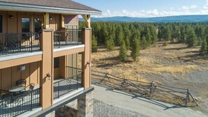 A two-story building with balconies, a gravel driveway, and a forested landscape in the background. - WorldMark Yellowstone - 1 Bedroom (West Yellowstone)