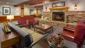 A spacious lobby with a stone fireplace, red upholstered chairs, and a wooden coffee table. - WorldMark Yellowstone - 1 Bedroom (West Yellowstone)