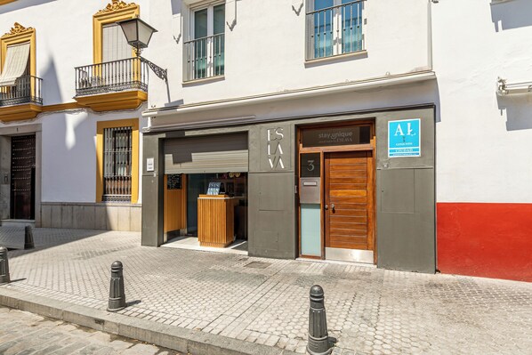 Un edificio con entrada a nivel de calle, puerta de madera y un letrero que indica que es un edificio residencial.