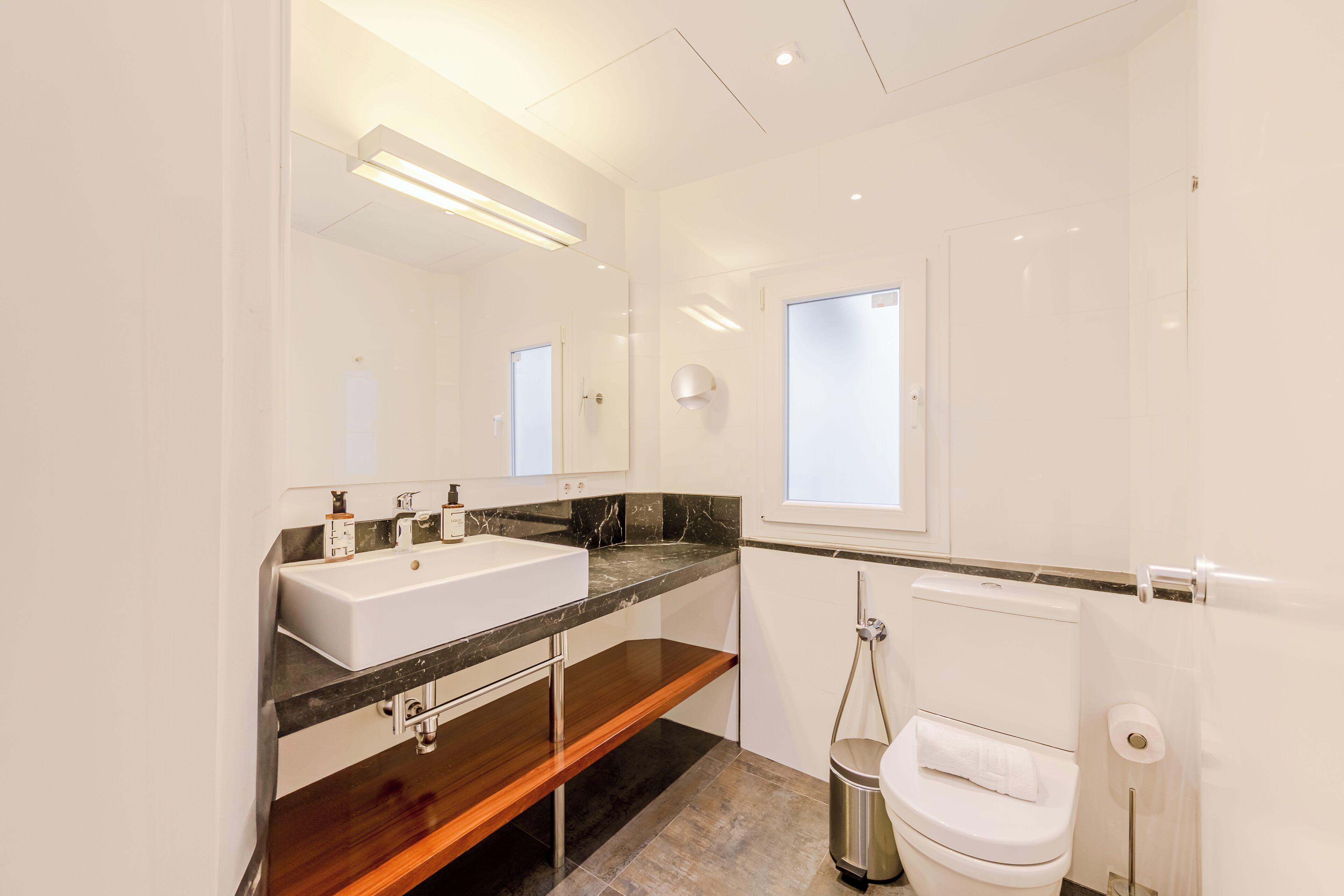 A modern bathroom with a double sink, a toilet, and a shower.