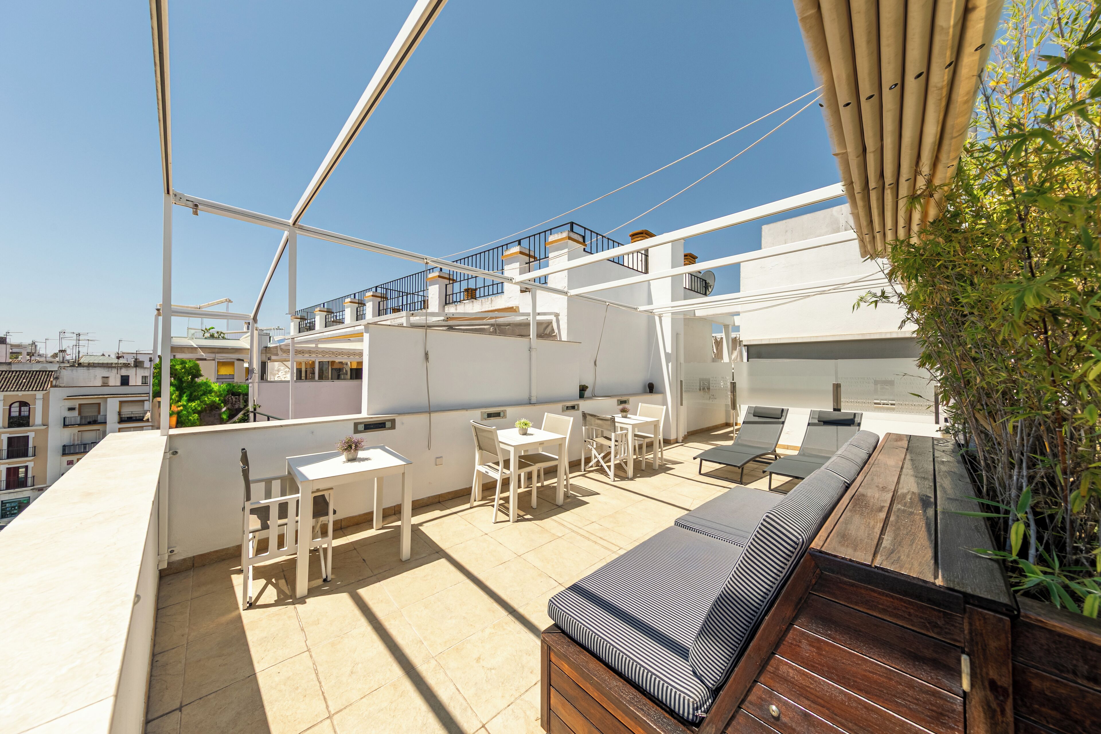 A rooftop terrace with a dining area, seating, and a wooden deck.
