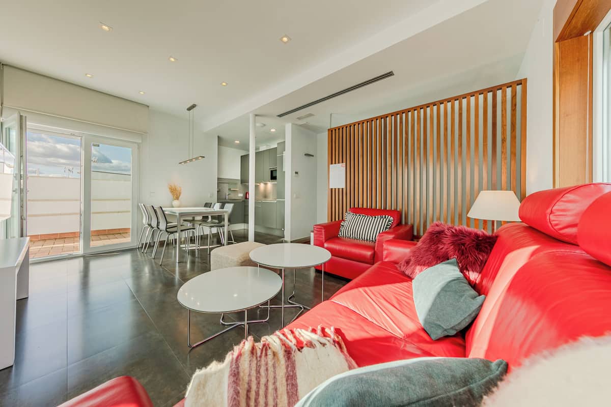Un salon moderne avec un canapé rouge, une table basse blanche et un séparateur de pièce en bois.