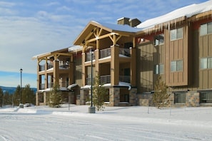 Ein mehrstöckiges Lodge mit Balkonen und einer Skipiste im Hintergrund.