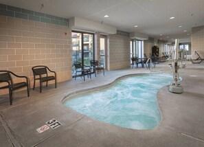 Ein Wellnessbereich mit Whirlpool, Fitnessgeräten und Sitzgelegenheiten.