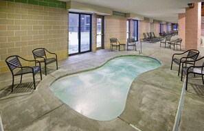 Un espace piscine avec des bords ondulés, entouré de chaises longues et d’un mur en briques.