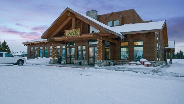 A log cabin-style building with a sign reading "Yellowstone MAX". - Yellowstone | Adventure Base Stay | Pool + Nature (West Yellowstone)