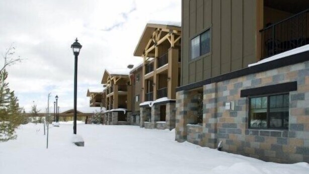 A snow-covered walkway leading to a building with multiple floors and balconies. - Yellowstone | Adventure Base Stay | Pool + Nature (West Yellowstone)