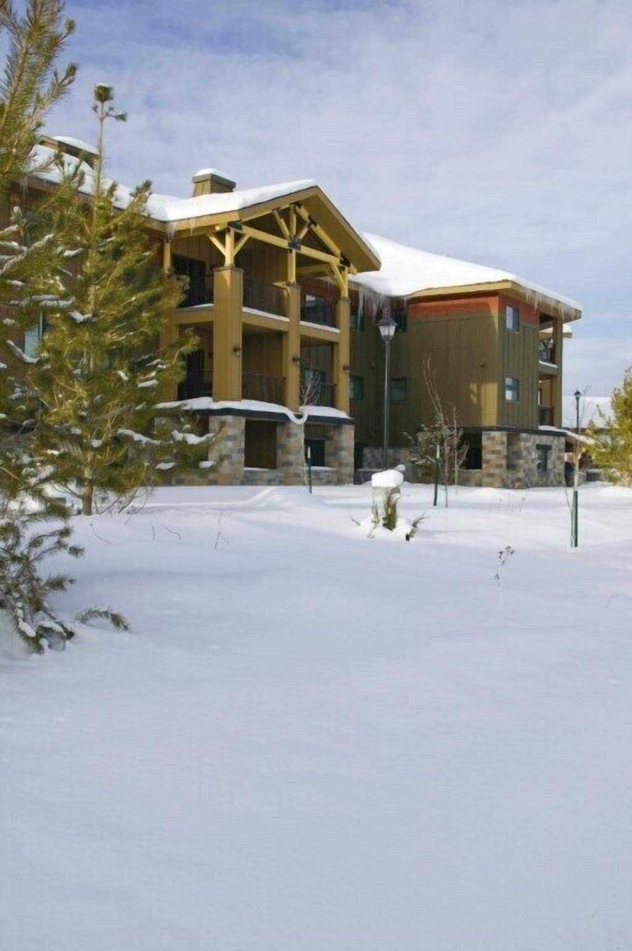 A multi-story building with a snow-covered roof and a stone facade.