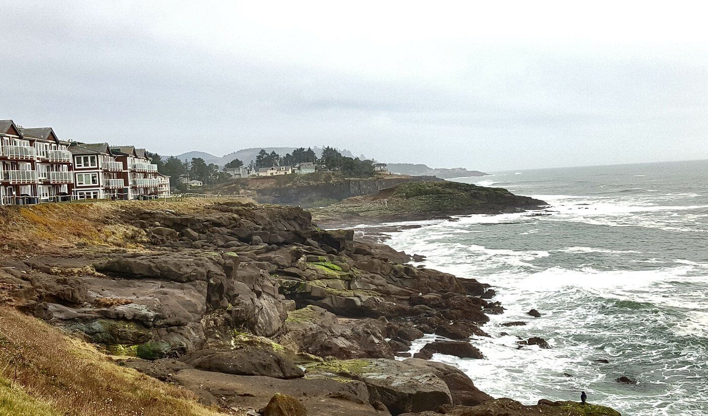 Ett bostadsområde vid kusten med en bergig terräng och utsikt över havet.