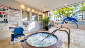 Area piscina con vasca idromassaggio, cartelli di sicurezza e una scultura a forma di delfino.
