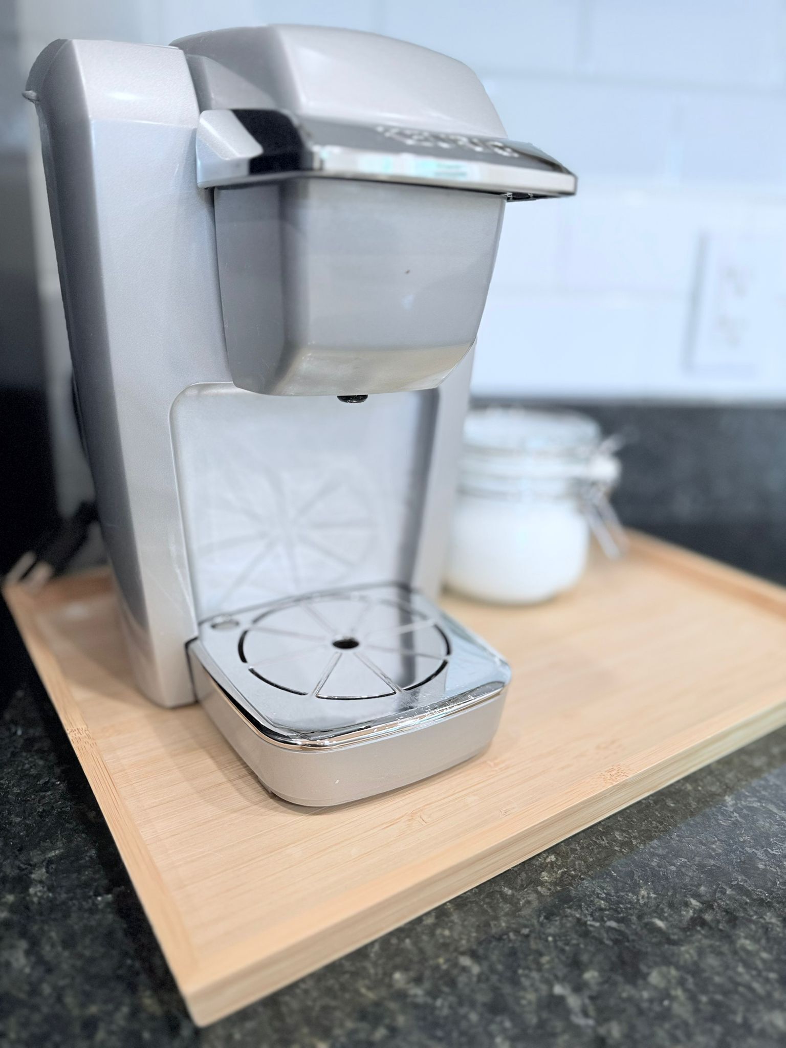 Una cafetera sobre una tabla de madera con un recipiente blanco al fondo.