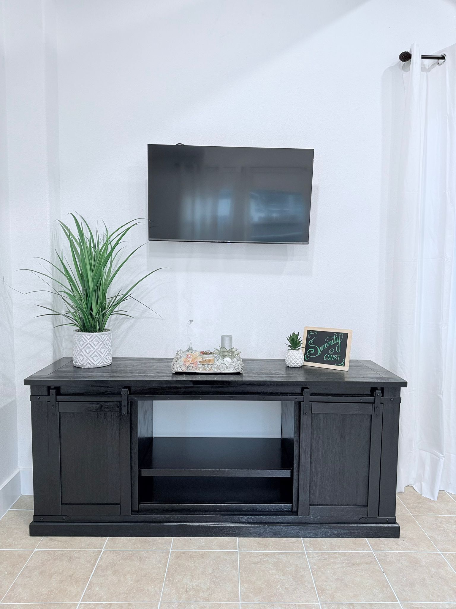 Een donkere houten tv-meubel met een flatscreen televisie erboven.