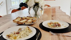 A dining table with plates of food, a vase of flowers, and a painting on the wall.