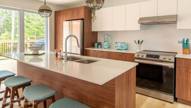 A modern kitchen with a large island, stainless steel appliances, and wooden cabinets.