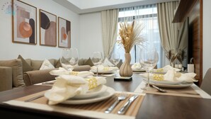 Ein Essbereich mit einem langen Tisch, gedeckt für sechs Personen, mit weißen Tellern, goldenen Servietten und klaren Weinkühlen.