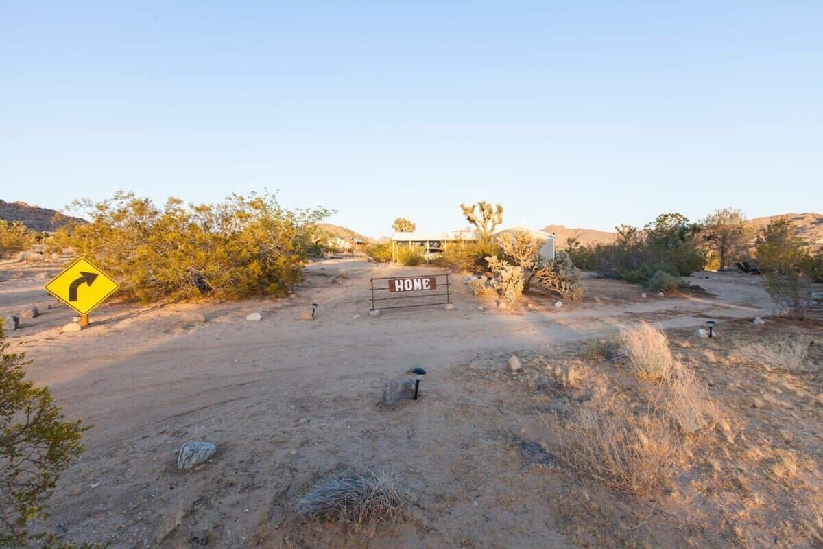 A desert landscape with a 'HOME' sign, a winding road sign, and sparse vegetation.