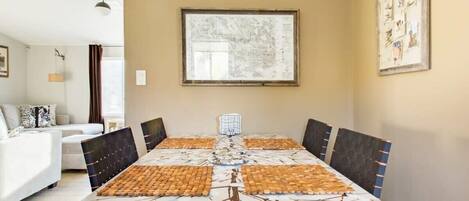 A dining area with a large table, chairs, and a map on the wall.
