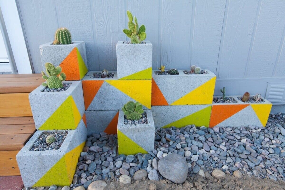 A series of concrete planters with cacti, arranged in a staggered pattern against a light blue wall.