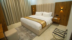 A modern hotel room with a large bed, wooden headboard, bedside tables, and a desk with a chair. - Maqam mostaqbal for serviced apartments (Ha'il)