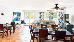 Amplia sala de estar con sofá, mesa de comedor, sillas y ventilador de techo.