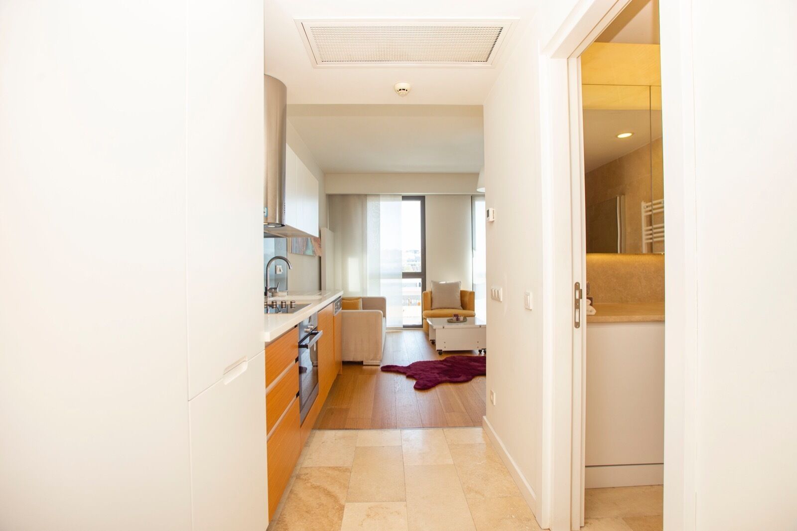 A modern kitchen with a built-in oven and a dining area with a sofa and a coffee table.