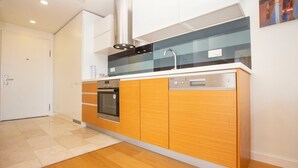 Une cuisine moderne avec des meubles en bois, un four en acier inoxydable, un lave-vaisselle et un pare-feu en verre.