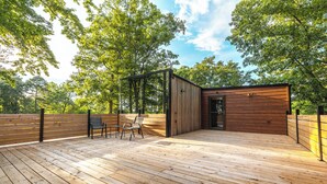 A wooden deck with a small building, a bench, and chairs. - Mo-ööd House Glamping/ Floating (Licking)