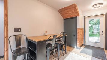 A dining area with a wooden table and four chairs, a black countertop, and a door with a glass panel.