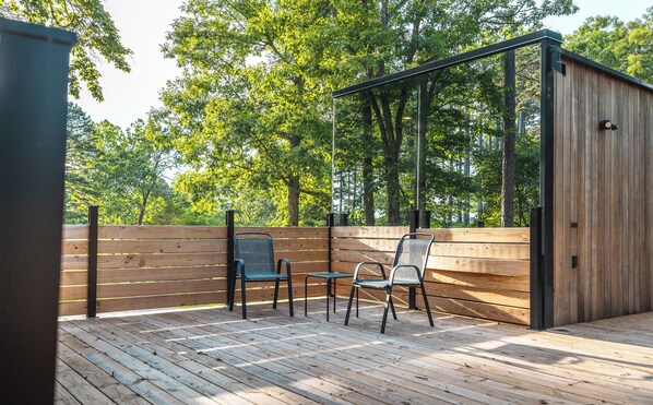 An outdoor patio with wooden flooring and two metal chairs.