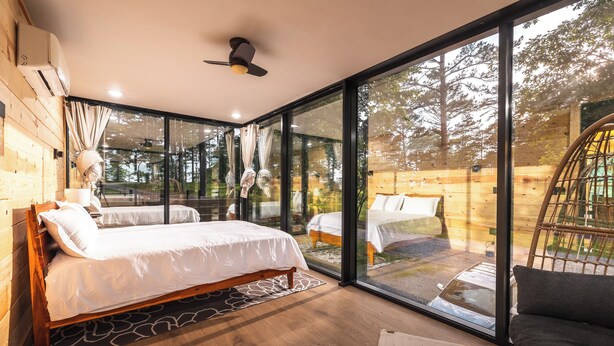 A modern bedroom with a large glass window, wooden flooring, and a bed with white bedding. - Mo-ööd House Glamping/ Floating (Licking)