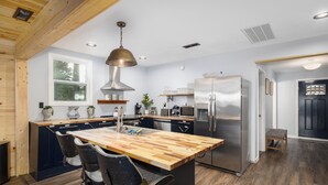 A modern kitchen with a wooden island, stainless steel appliances, and a large window. - Floating and Glamping at Big Piney River (Licking)